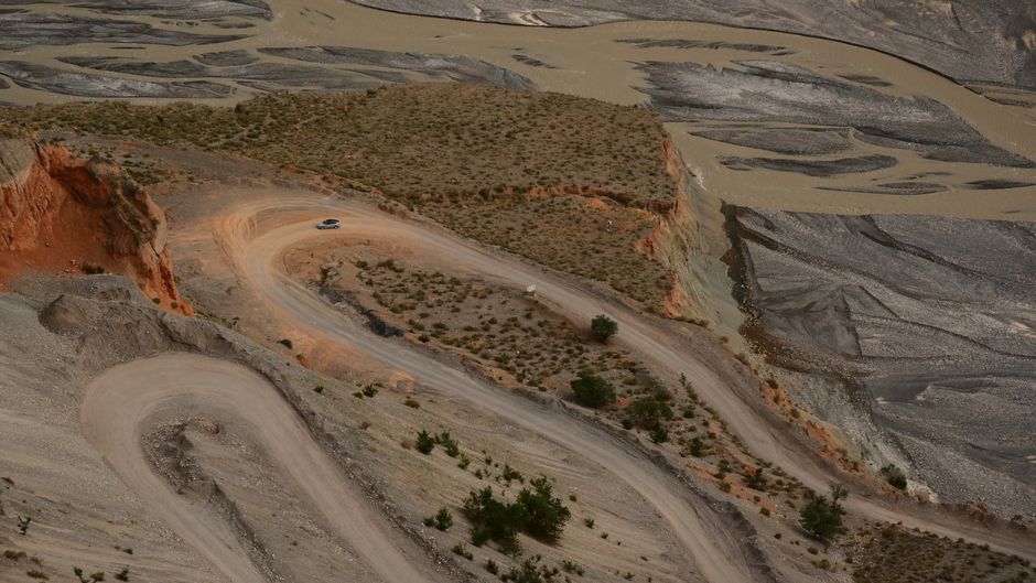 Aerial view of a winding road through Xinjiang's desert landscape with unique geological formations.