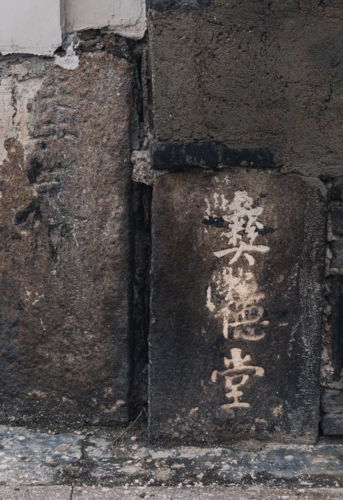Free Detail of an old stone wall with weathered Chinese characters in urban setting. Stock Photo