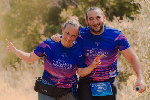 Free Two adult marathon runners in bright purple jerseys pose happily during an outdoor trail race. Stock Photo