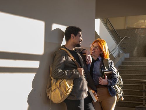 Free Two students chat and share a laugh in a sunlit stairwell at a Buenos Aires academic facility. Stock Photo