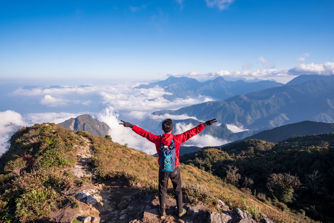 Free Photo of Man Standing on Mountain While Doing Peace Sign Stock Photo