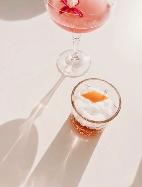 Overhead of elegant glassware with assorted alcoholic cocktails placed on white table in bright sunlight