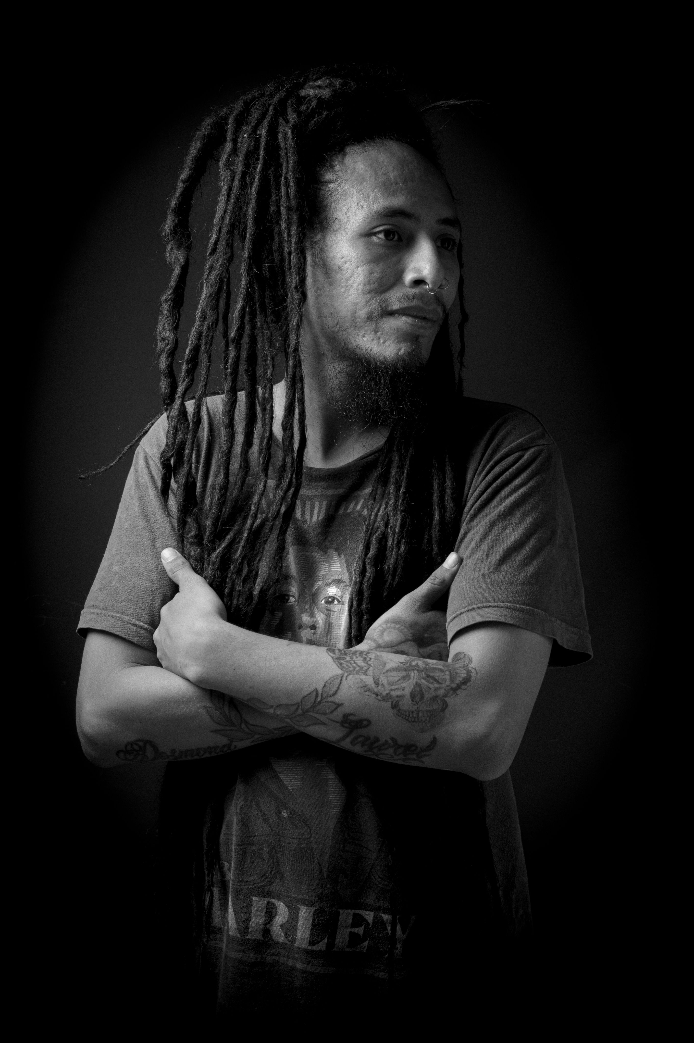 Black and white portrait of a man with dreadlocks and tattoos, conveying a cool, artistic vibe in Mexico.
