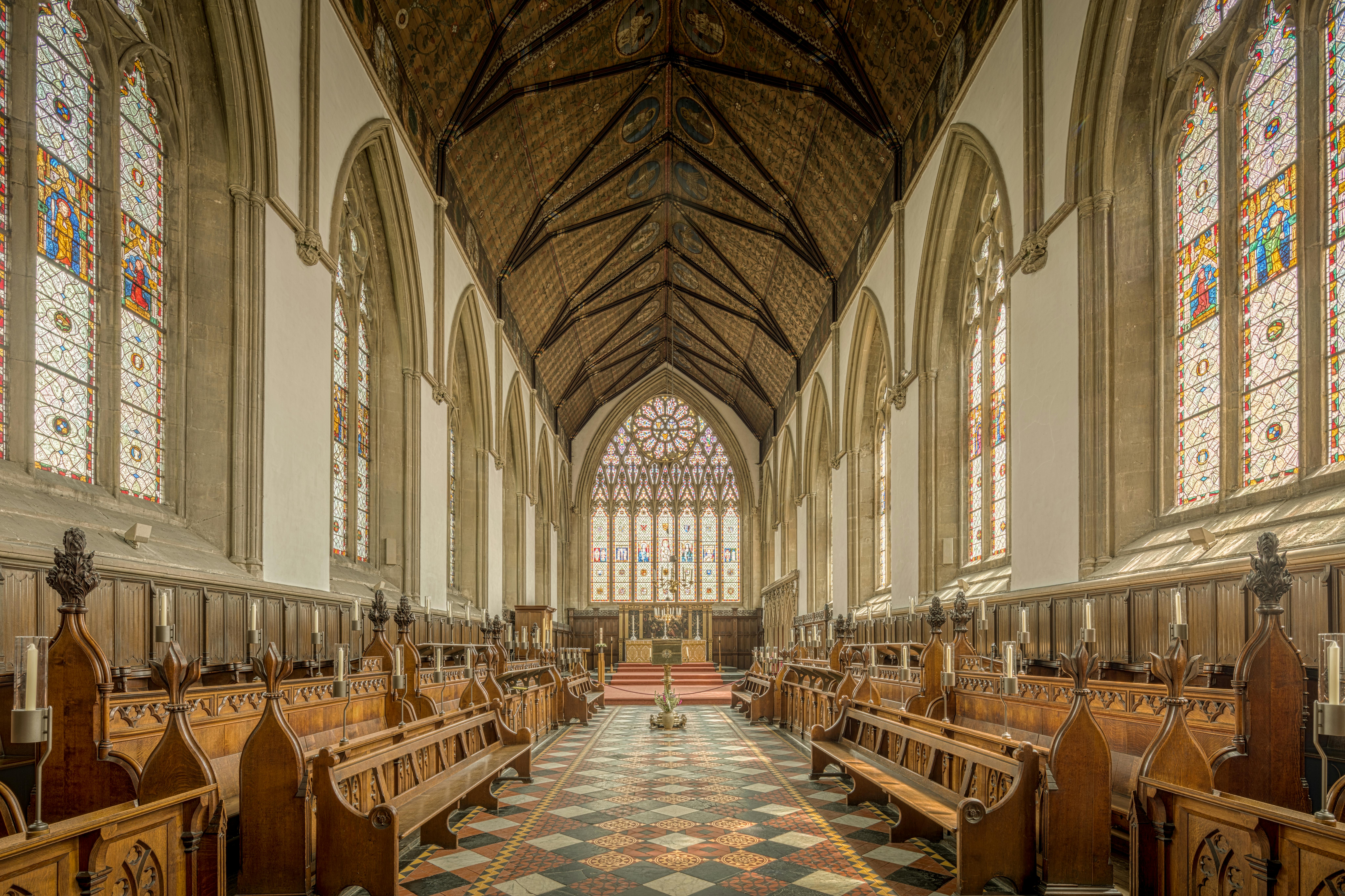 The stunning interior of Merton College Chapel featuring stained glass windows and wooden pews in Oxford, UK.