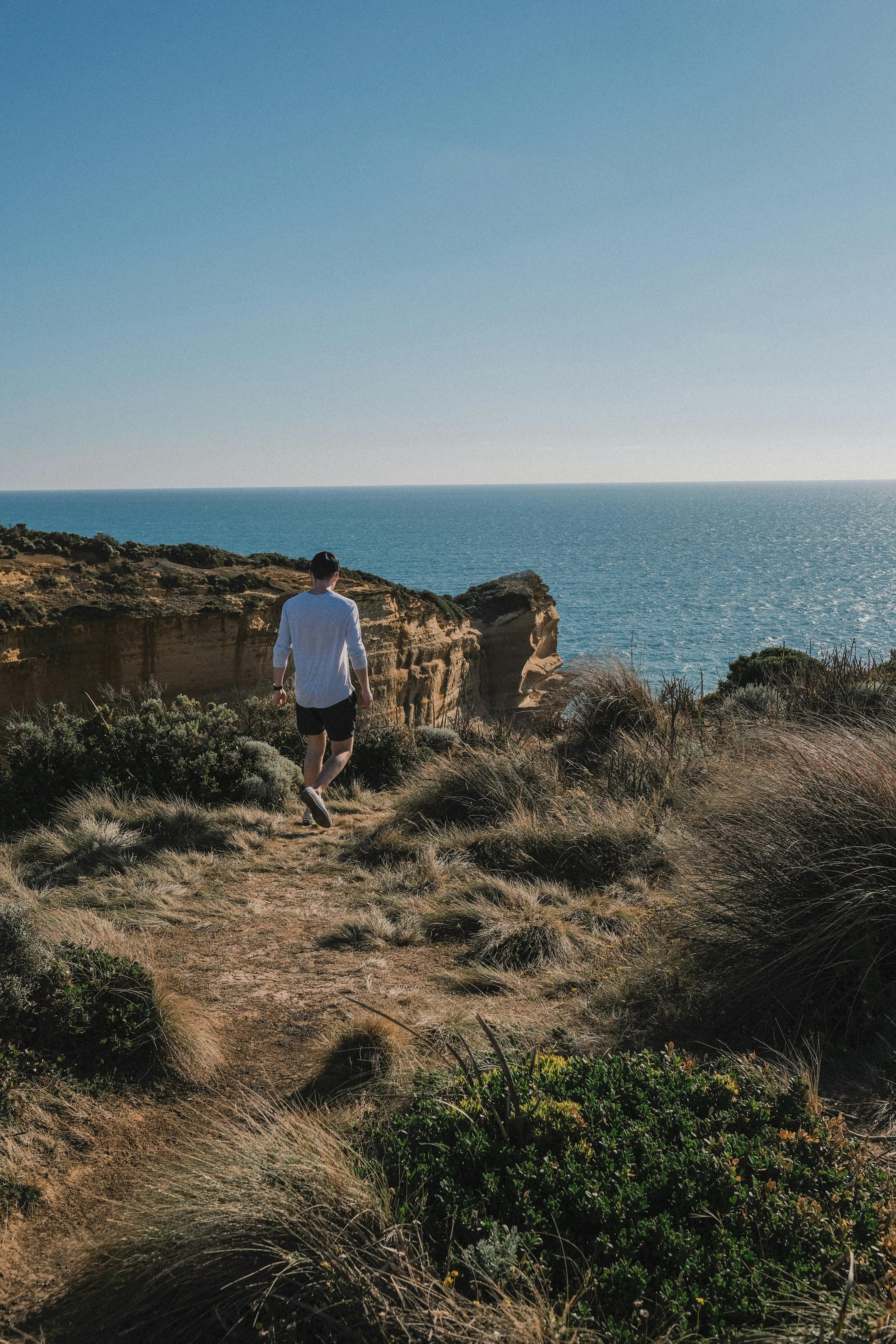 一名男子行走在澳大利亚的悬崖上，俯瞰大海，捕捉着宁静的沿海景色