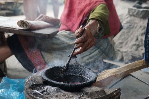 Artisan hand dipping tools in indigo dye, showcasing the traditional textile craft of Lung Tam, Vietnam.