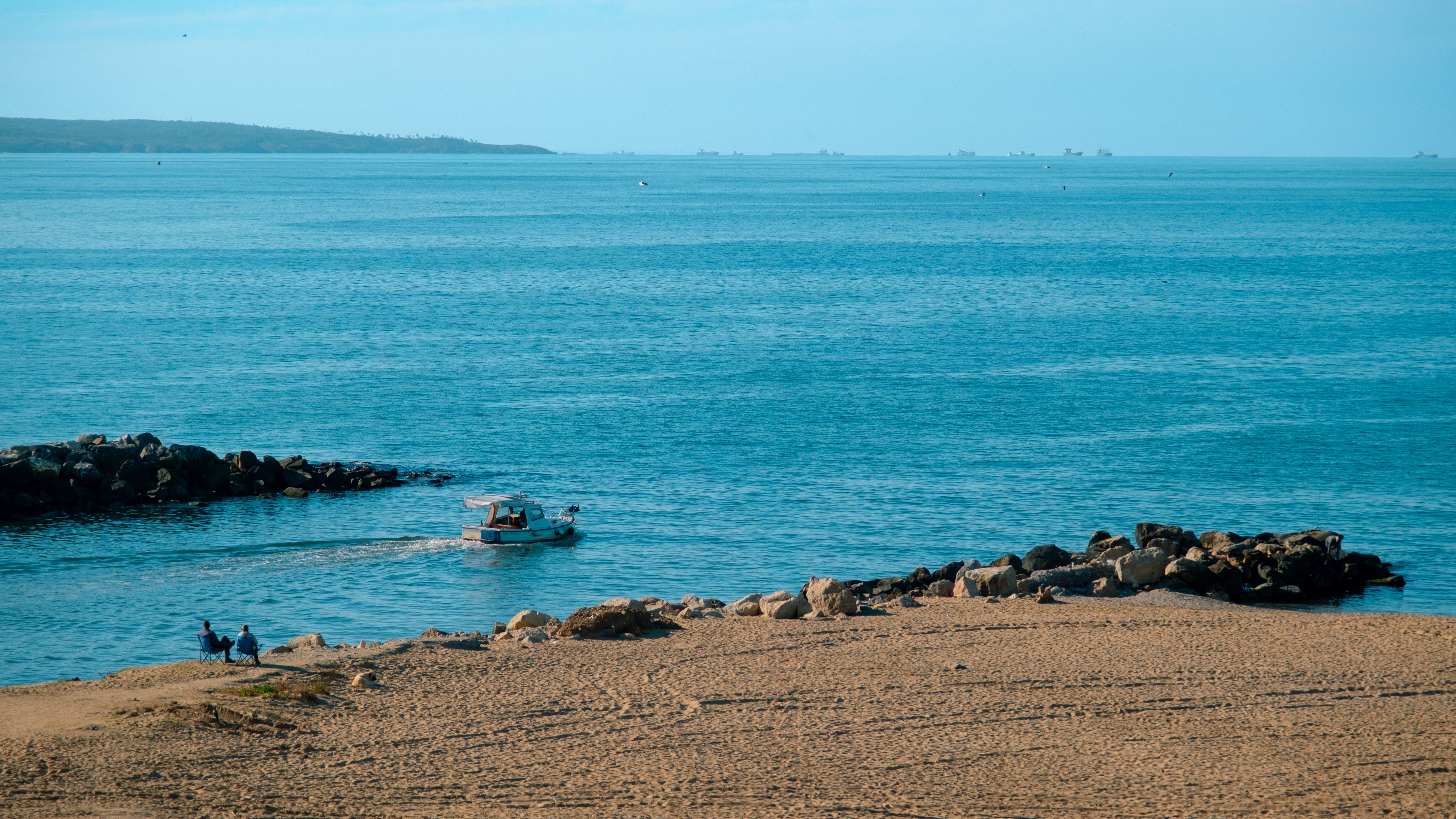 Tranquil beach scene in Riva, Istanbul with a boat on the water and rocky shores.