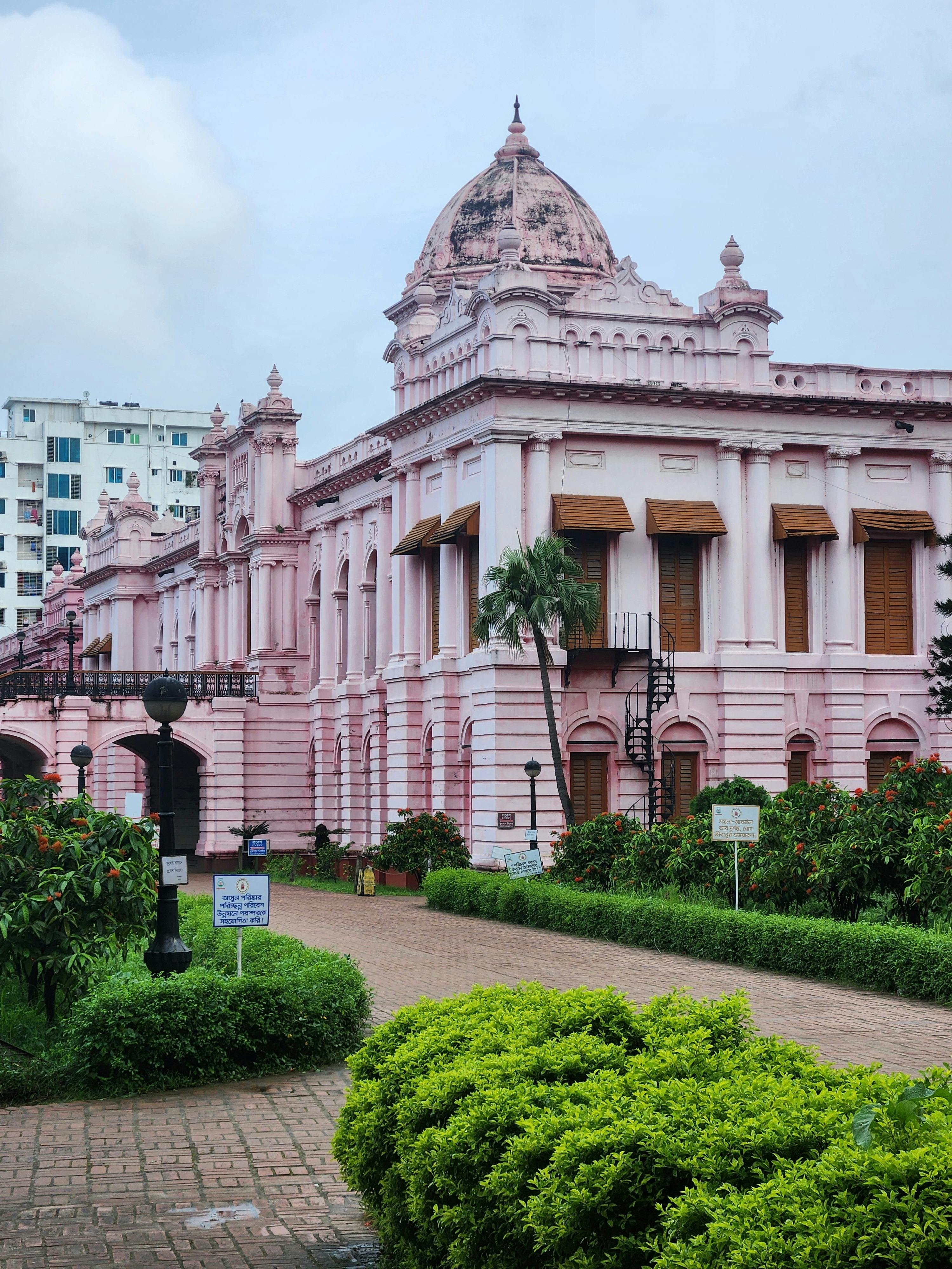 The iconic pink Ahsan Manzil in Dhaka, Bangladesh, surrounded by lush gardens and vibrant greenery.