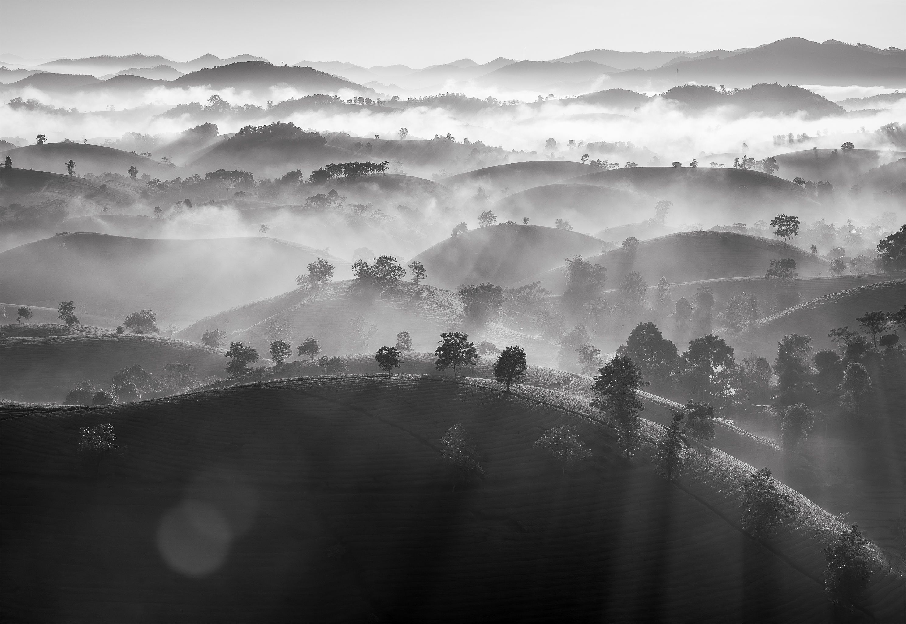 Captivating black and white landscape of misty hills and sun rays in Long Cốc, Phú Thọ, Vietnam.