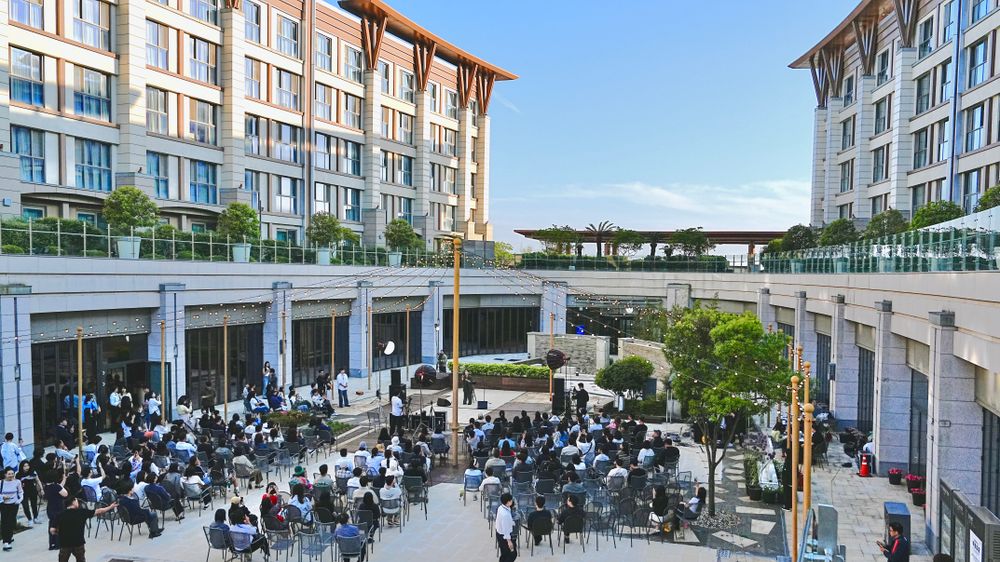Guests seated in a courtyard listening to speakers at an outdoor company event
