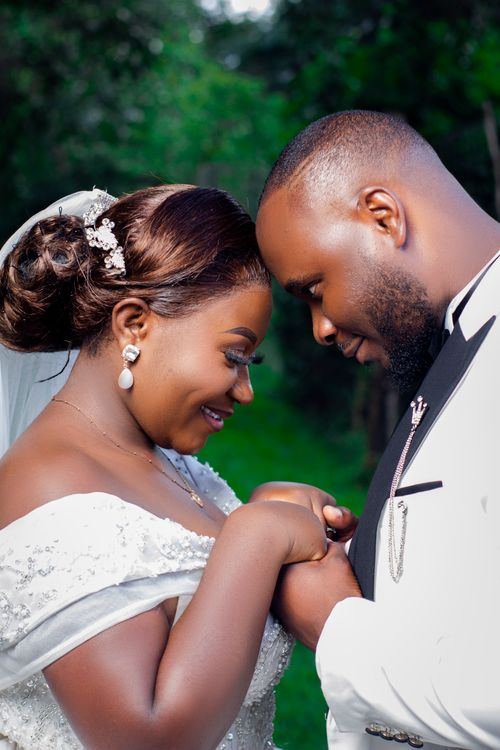 Free Outdoor wedding photo of a joyful couple in elegant attire, embracing and smiling. Stock Photo