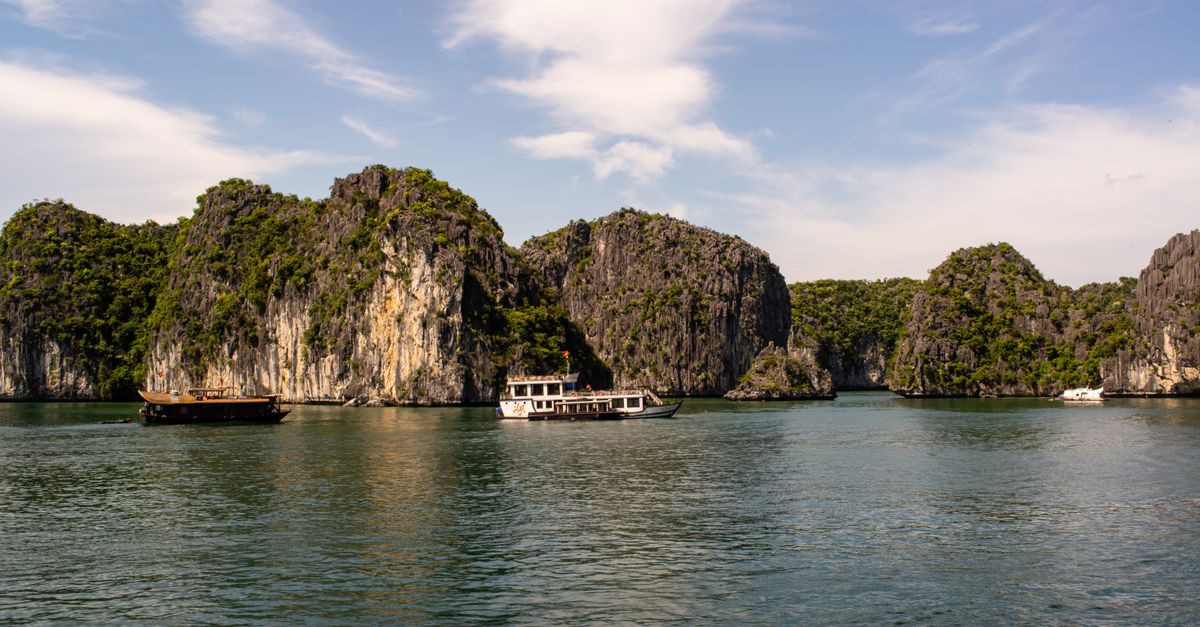Stunning limestone karsts and boats in Ha Long Bay, Vietnam, under a clear sky.