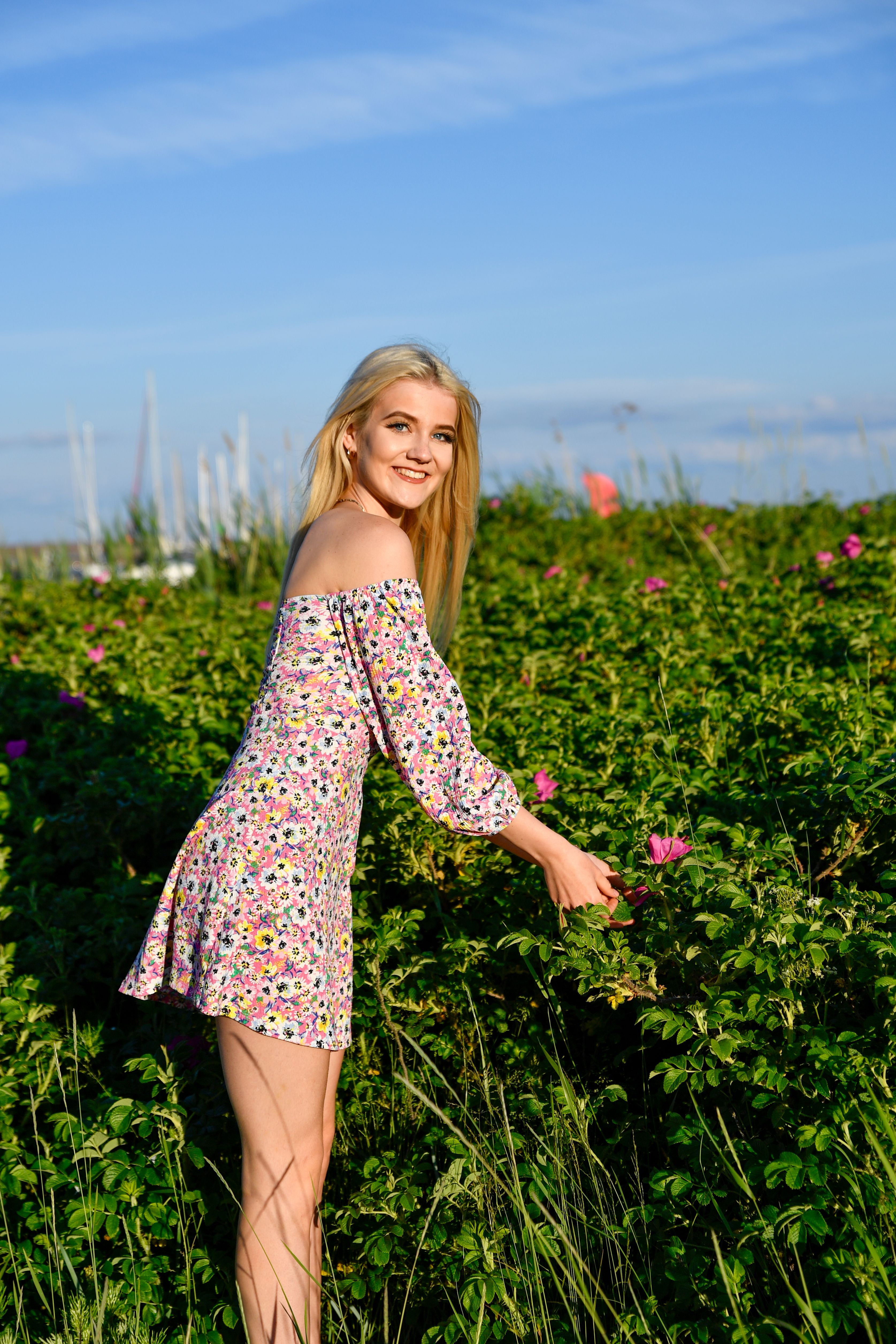Blonde woman in floral dress enjoying summer day in Estonian countryside.