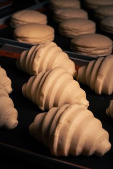 Close-up of croissant and macaron dough on baking trays ready to be baked, highlighting texture.