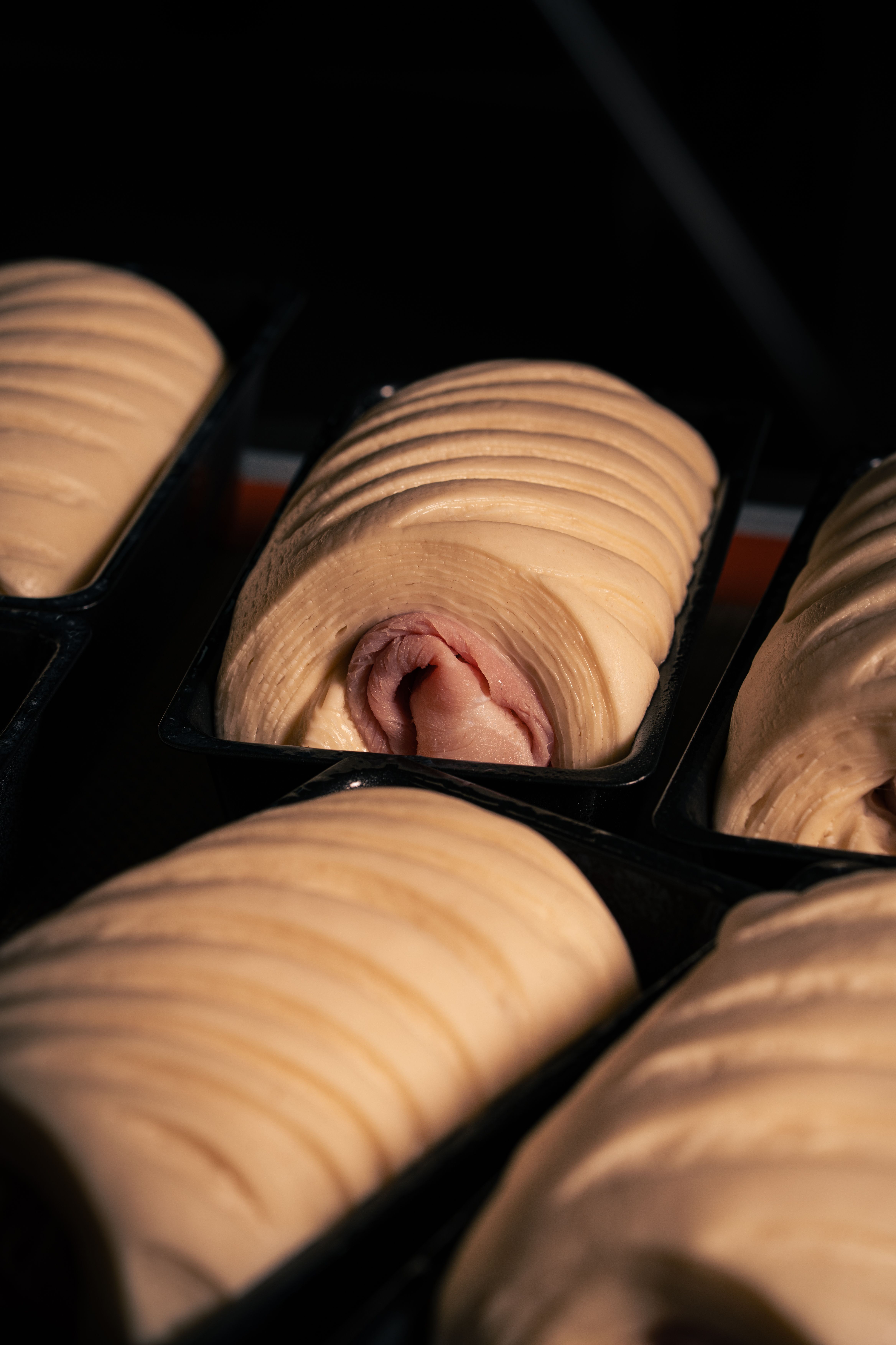 Detailed view of prepared pastry dough in trays with visible slices of ham, ready for baking.