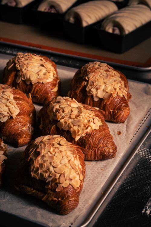 Free Delicious almond croissants topped with almonds, freshly baked in a bakery setting. Stock Photo
