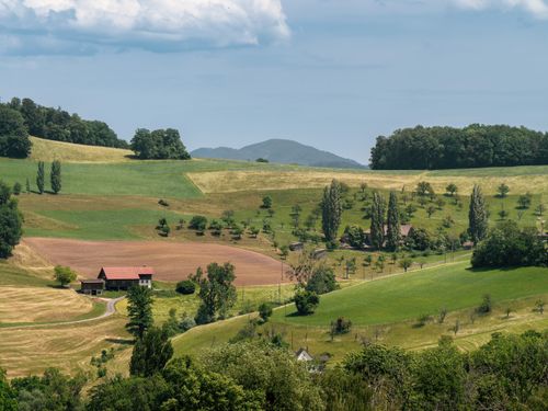 Free Beautiful rural landscape with farms and rolling hills under a blue sky. Stock Photo