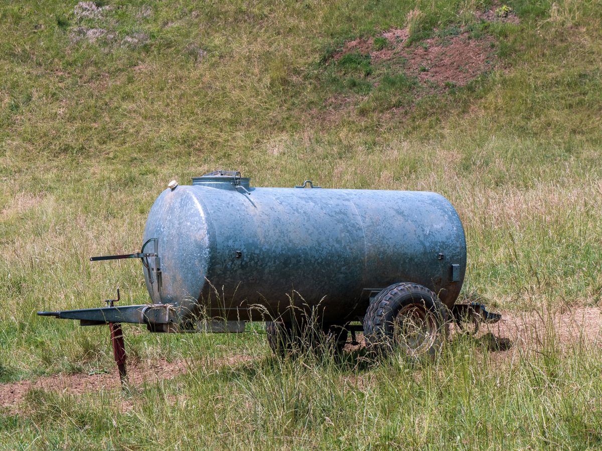 Person adding water treatment drops to storage container