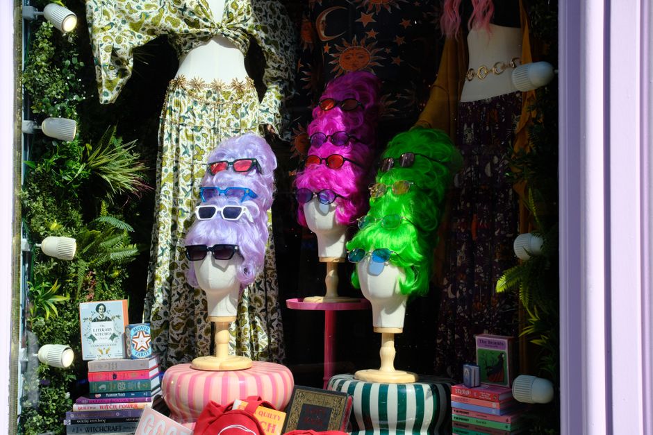 A lively storefront in Edinburgh featuring mannequins with colorful wigs and sunglasses.