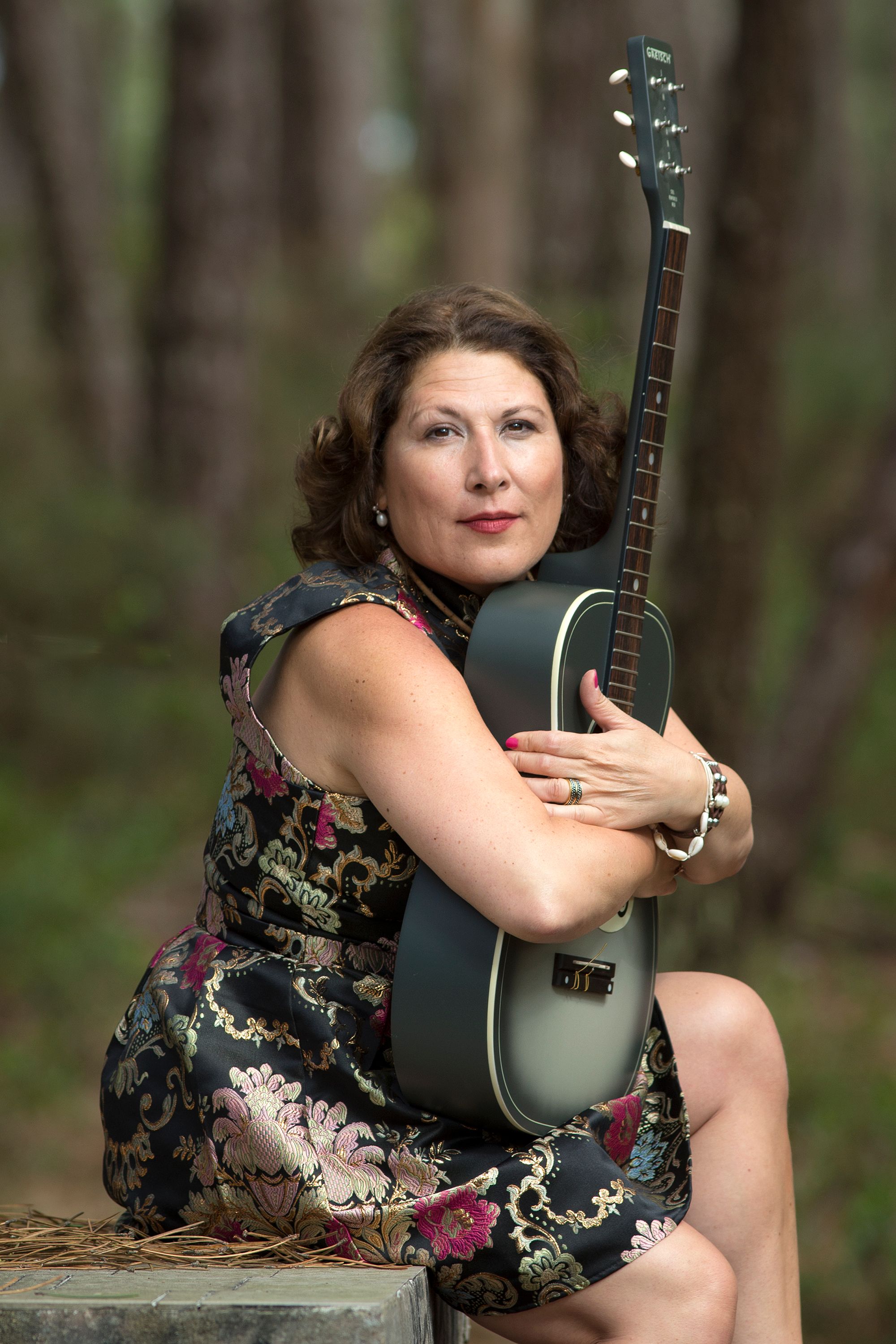 A woman embraces a guitar in a tranquil forest setting, evoking harmony and peace.
