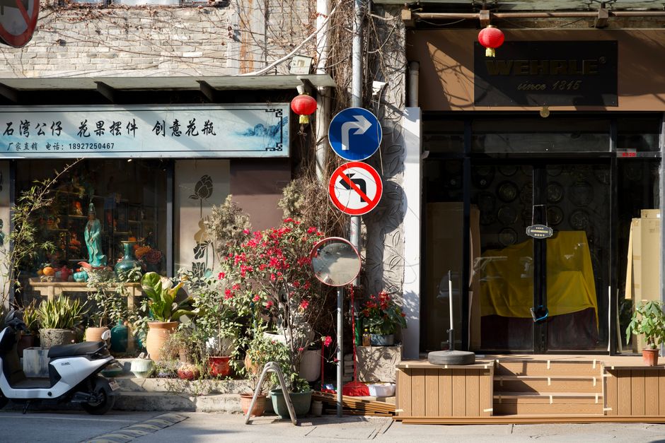 A vibrant street scene of a Chinese shopfront decorated with plants and signs, capturing cultural essence.