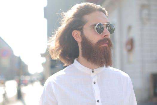 一位留着长发和胡须的时尚男子在户外戴着太阳镜
