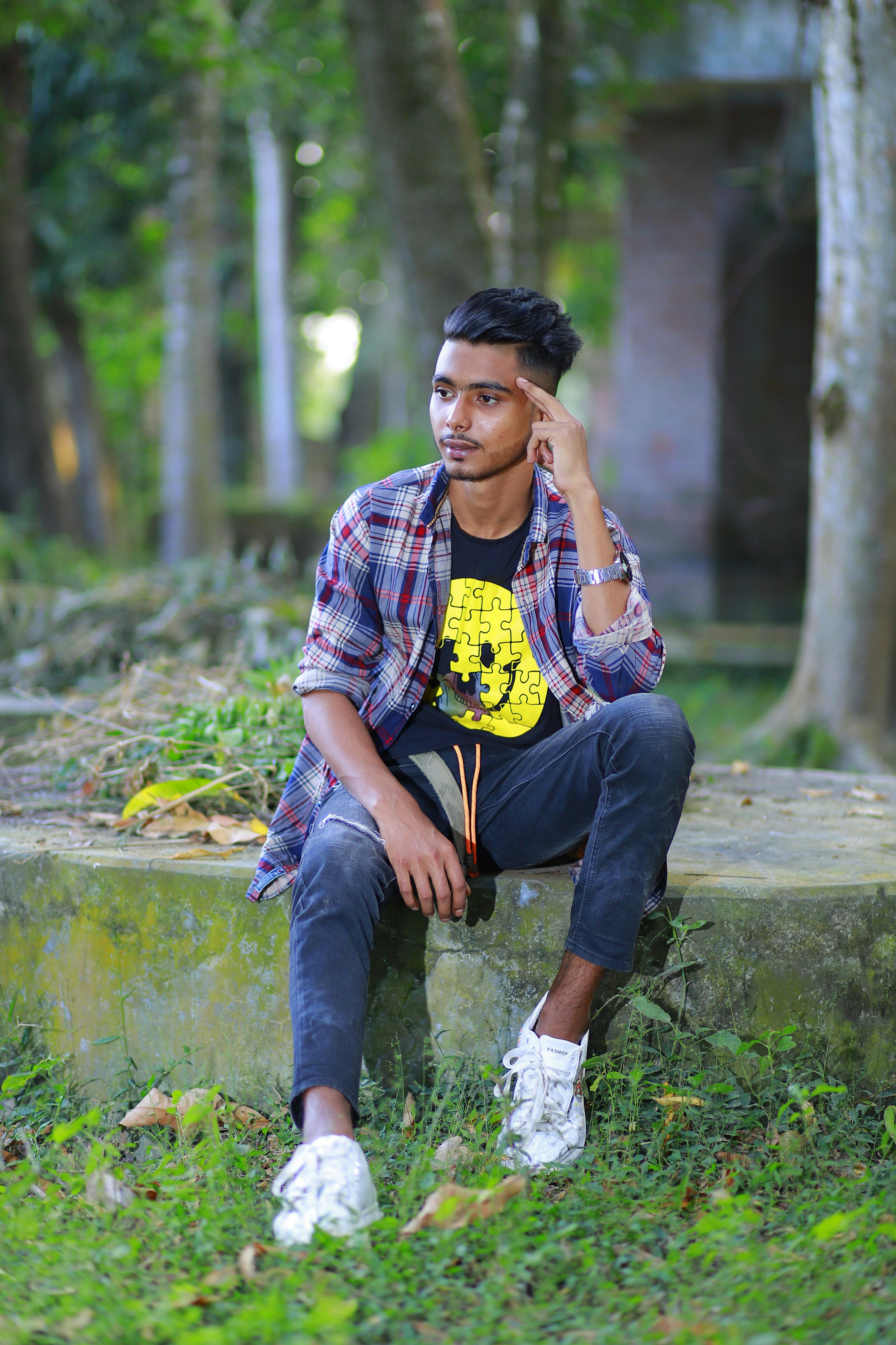 A young man sitting outdoors in nature looking thoughtful in Bangladesh.