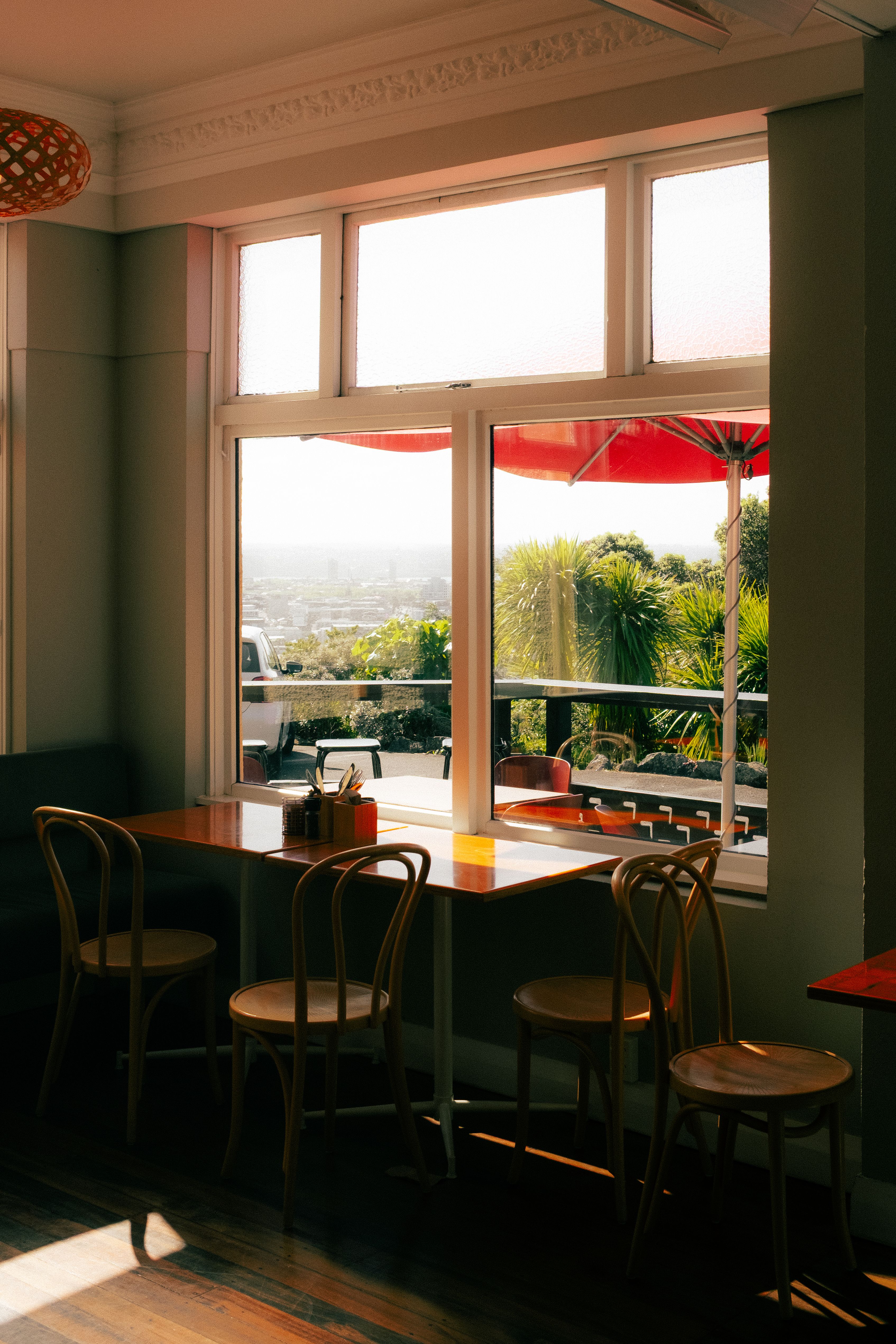 A cozy coffee shop in Auckland with a scenic view, wooden chairs, and ambient lighting.