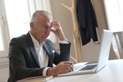 Man in Black Suit Jacket While Using Laptop