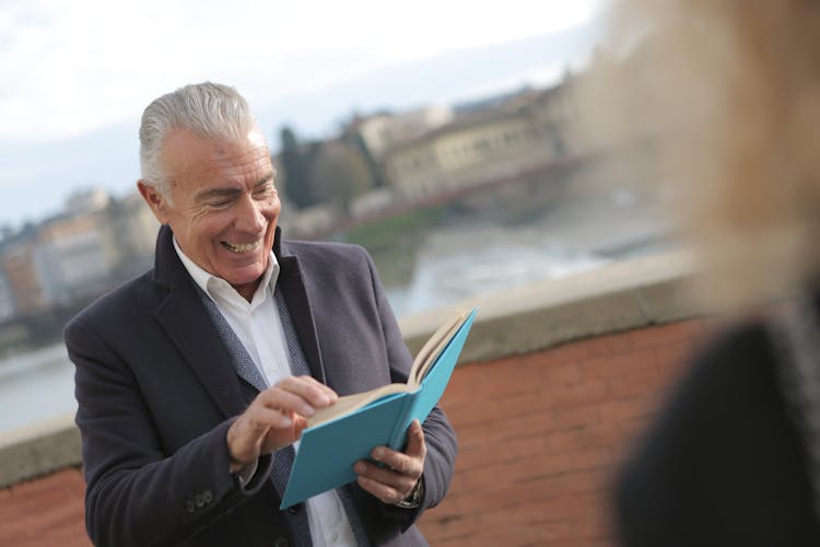 Man In Black Suit Holding Blue Book