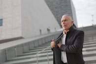 一位穿着时尚外套的男士，自信地站在现代建筑旁