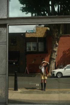 Reflection of a person in a city street, capturing urban life in London.