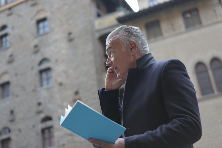 Man In Black Suit Holding Blue Book