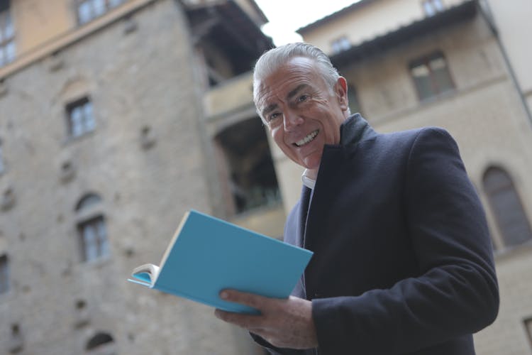 Man In Black Suit Holding Blue Book