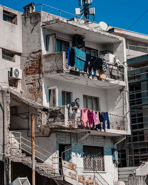 Free An urban apartment facade showing balconies with hanging laundry and a person standing. Stock Photo