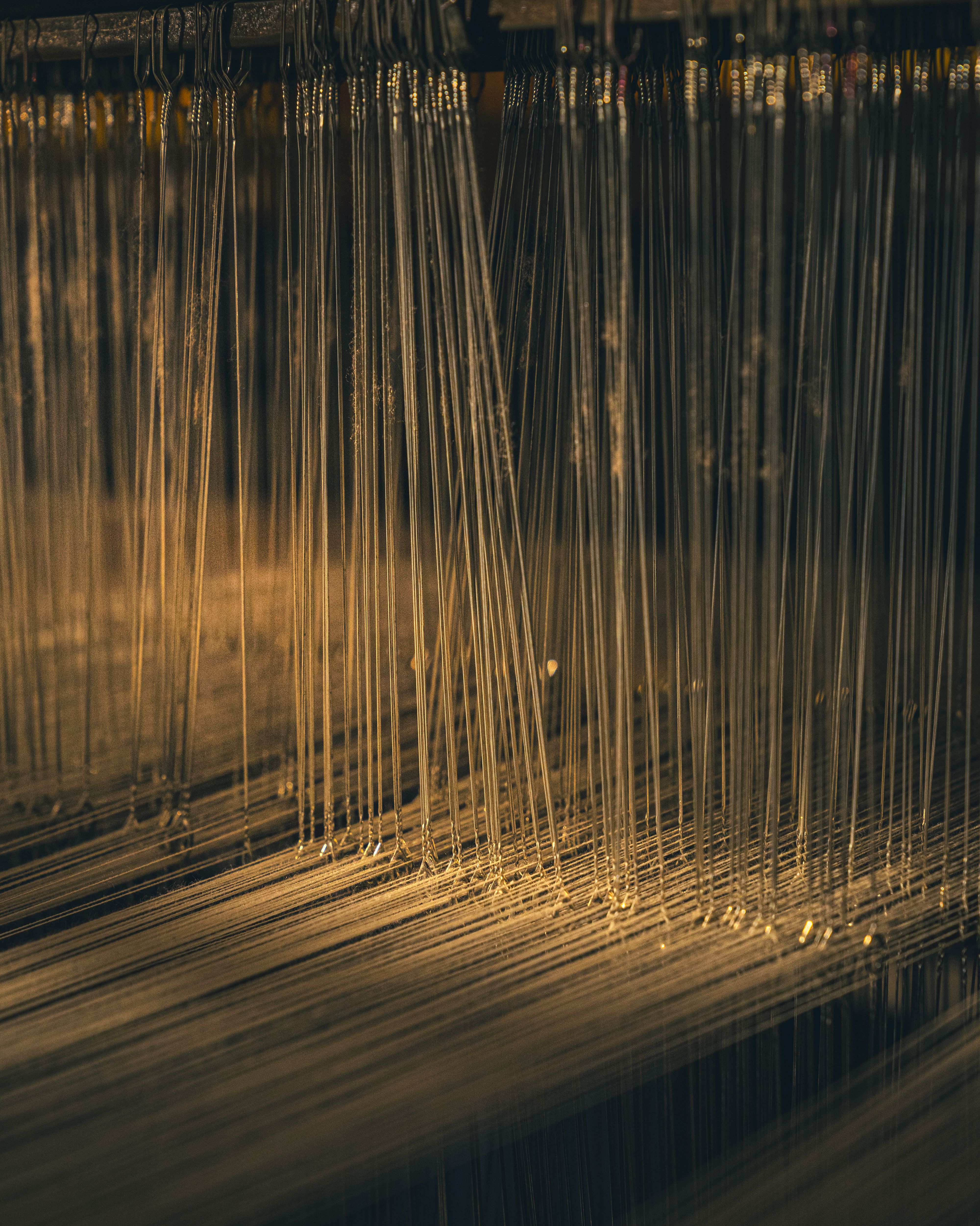 Detailed view of threads on a weaving loom, highlighting the textile manufacturing process.