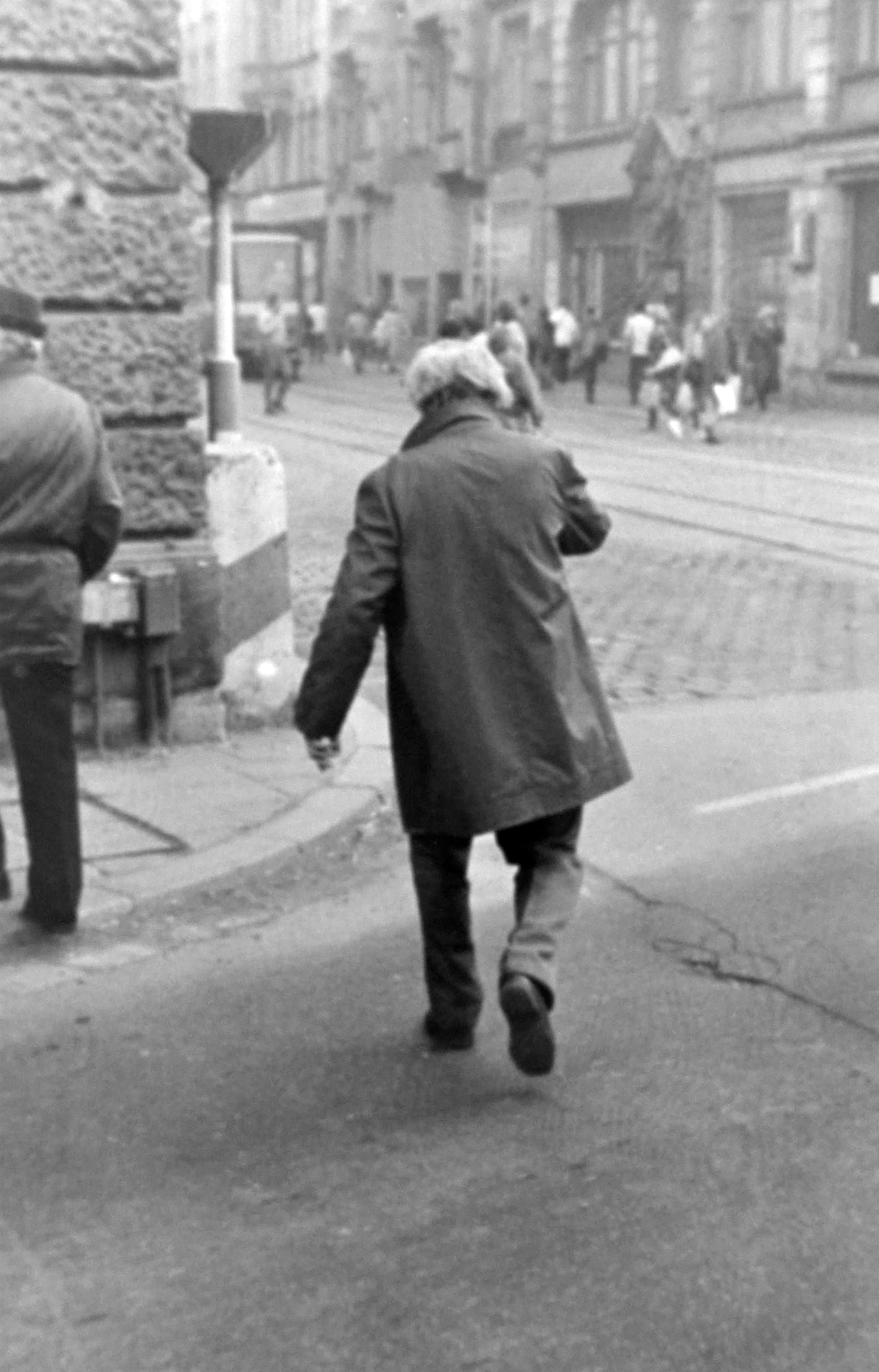 Black and white photo of a man walking on a busy city street.