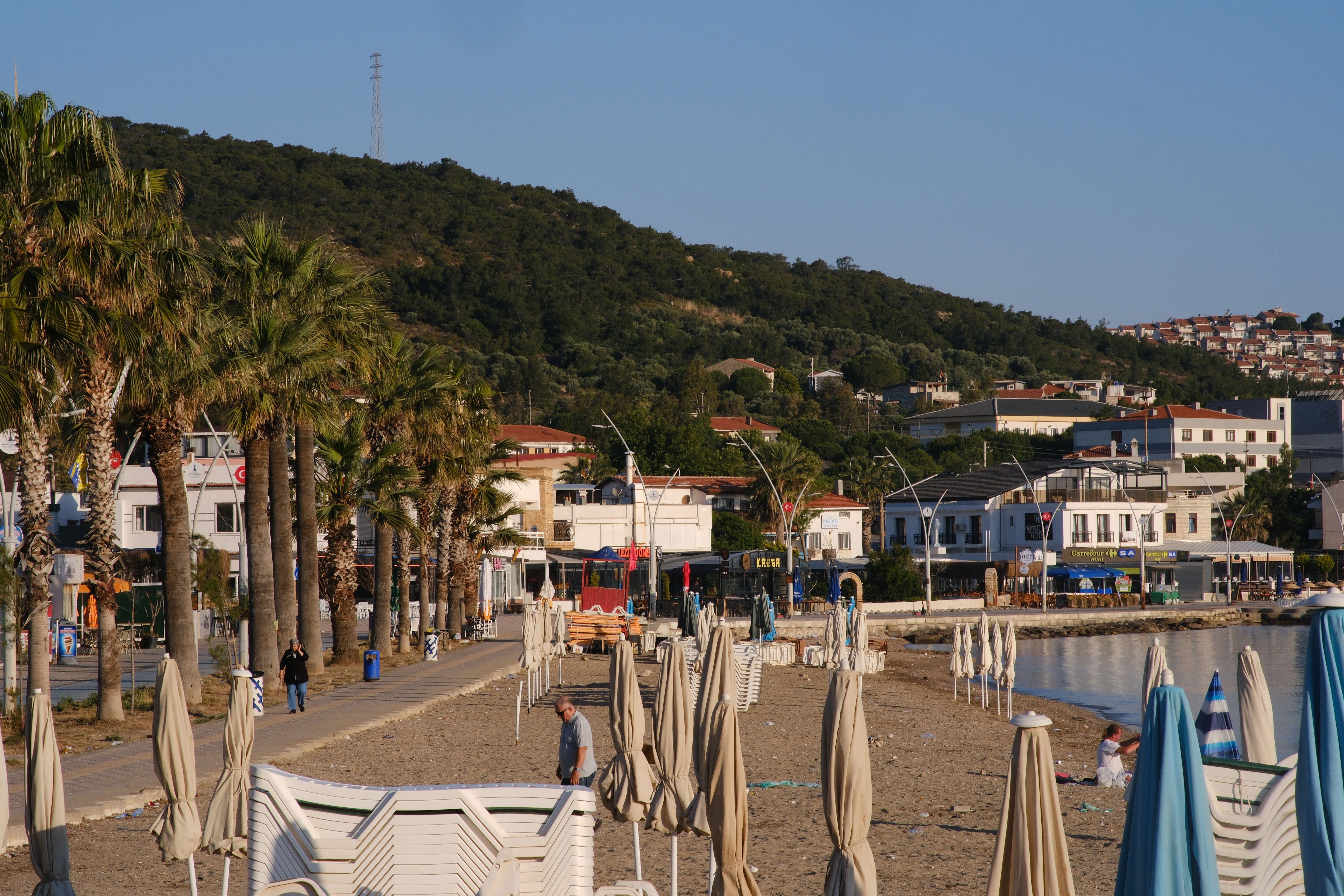 Scenic view of the beachfront promenade in Foça, İzmir, Türkiye with palm trees and umbrellas. — Trójmiasto