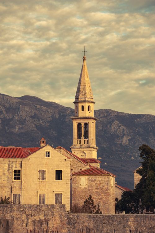 Free Charming historic bell tower with mountainous background, ideal for travel and architecture enthusiasts. Stock Photo