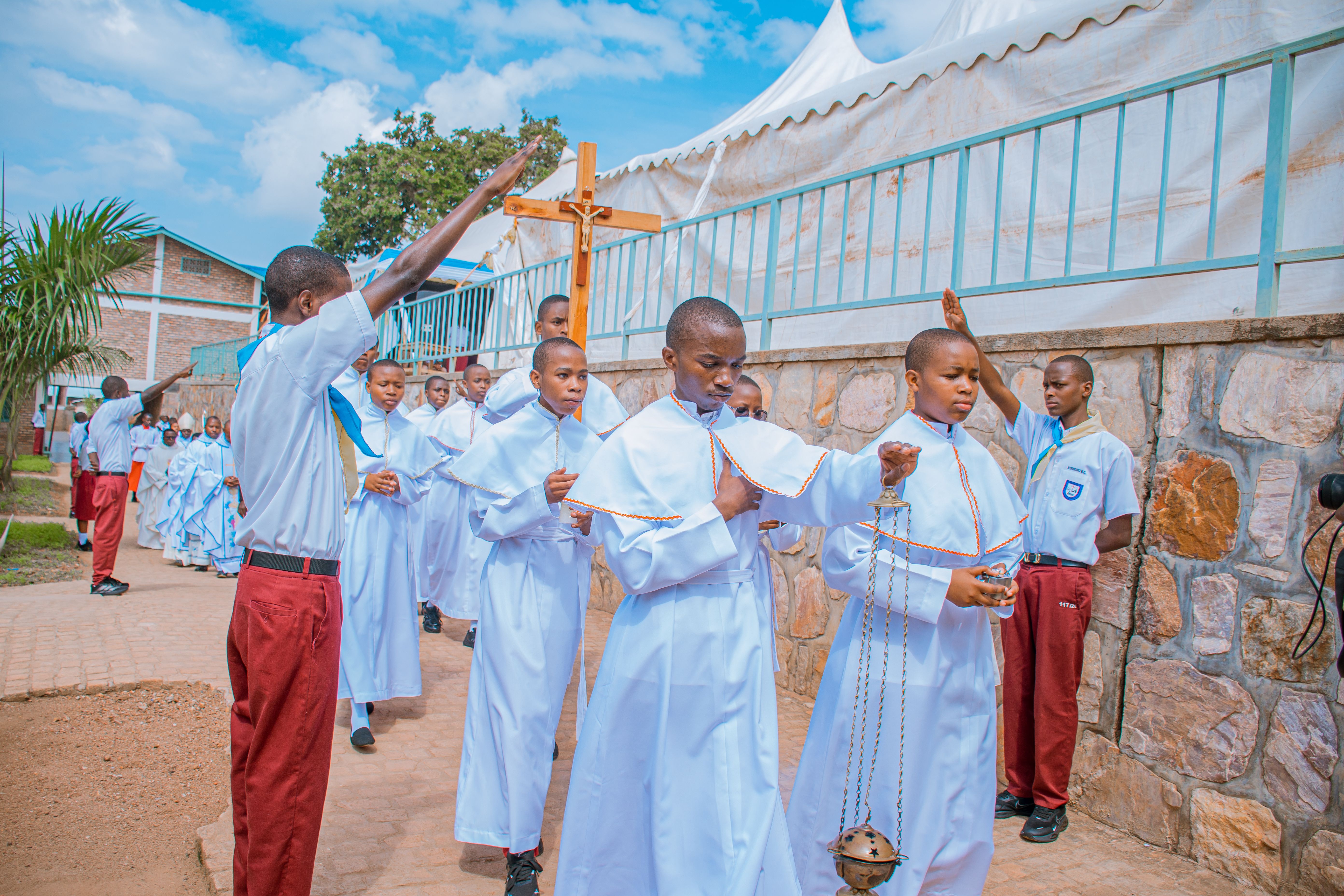 Youth participate in a religious procession outdoors, dressed in ceremonial robes, with a focus on spirituality and community.