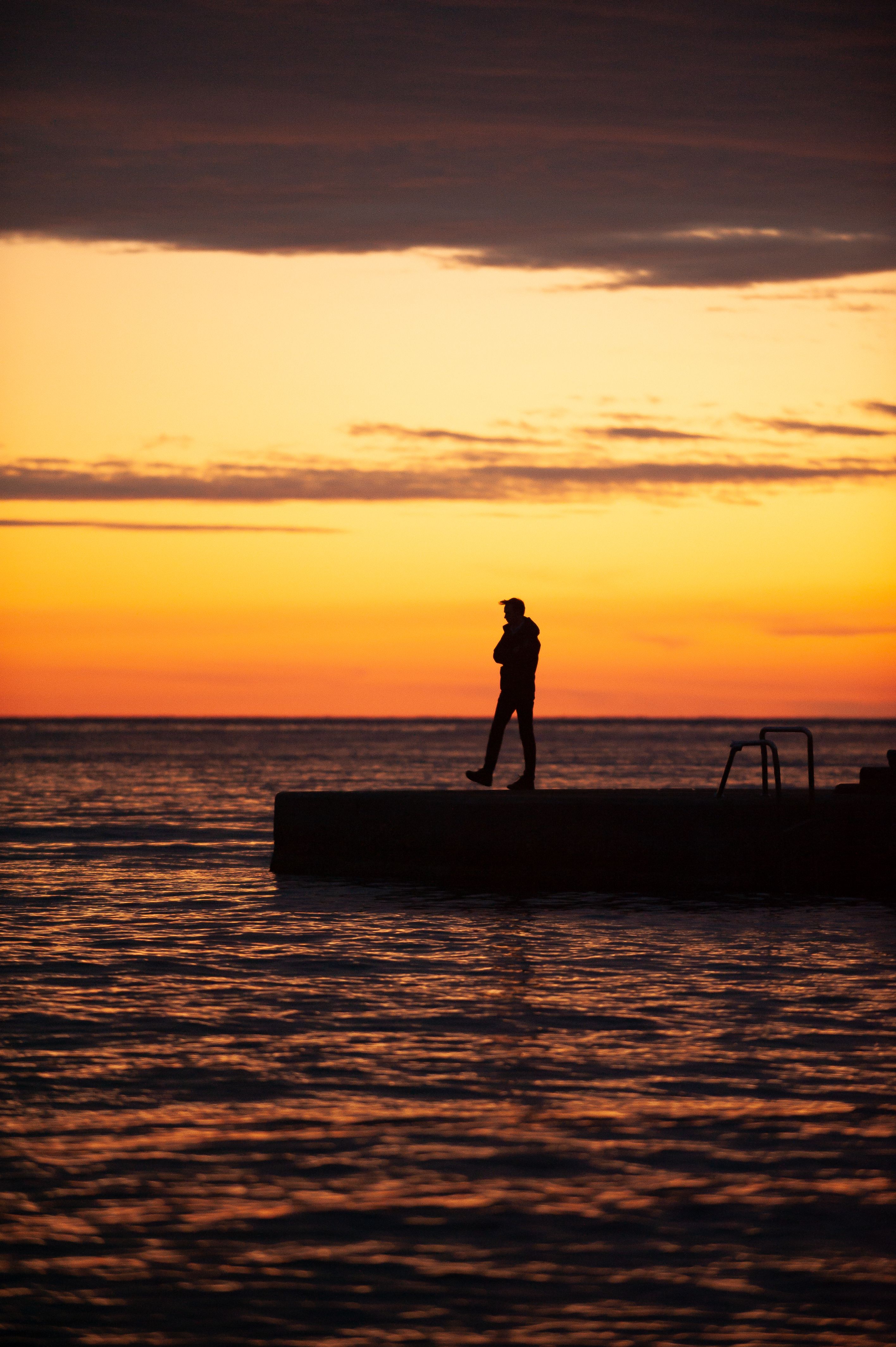 Silhouette of Man Standing on Wooden Dock during Sunset · Free Stock Photo