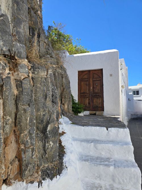 Free Whitewashed stone building with weathered wooden door in a sunny Mediterranean setting. Stock Photo