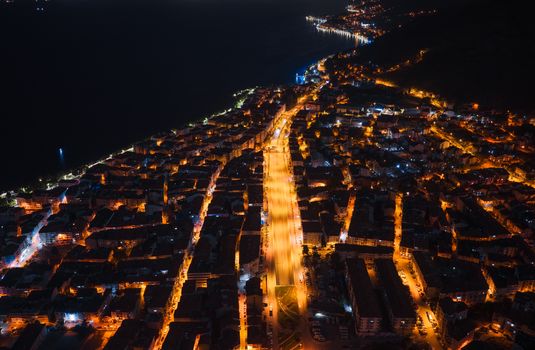 Stunning aerial night view of a city's illuminated streets and coastline, showcasing urban vibrancy.