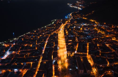 Free Stunning aerial night view of a city's illuminated streets and coastline, showcasing urban vibrancy. Stock Photo