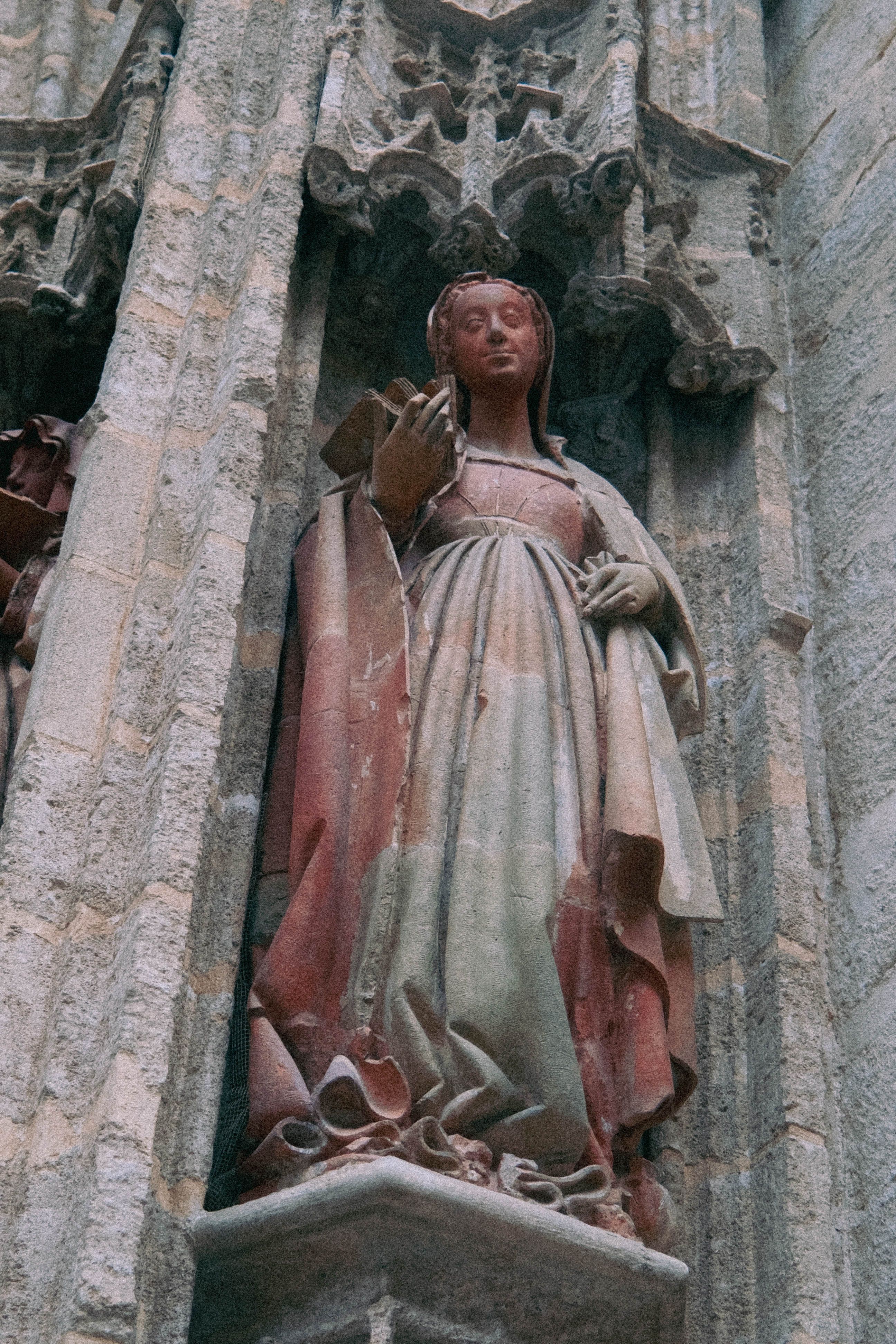 Historic Gothic stone statue on cathedral facade in Seville, reflecting Spanish architecture.