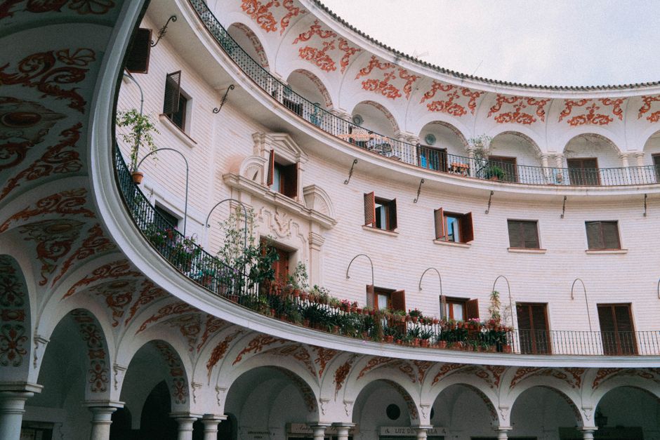 Elegant circular courtyard with ornate arches and balconies in Seville, Spain.