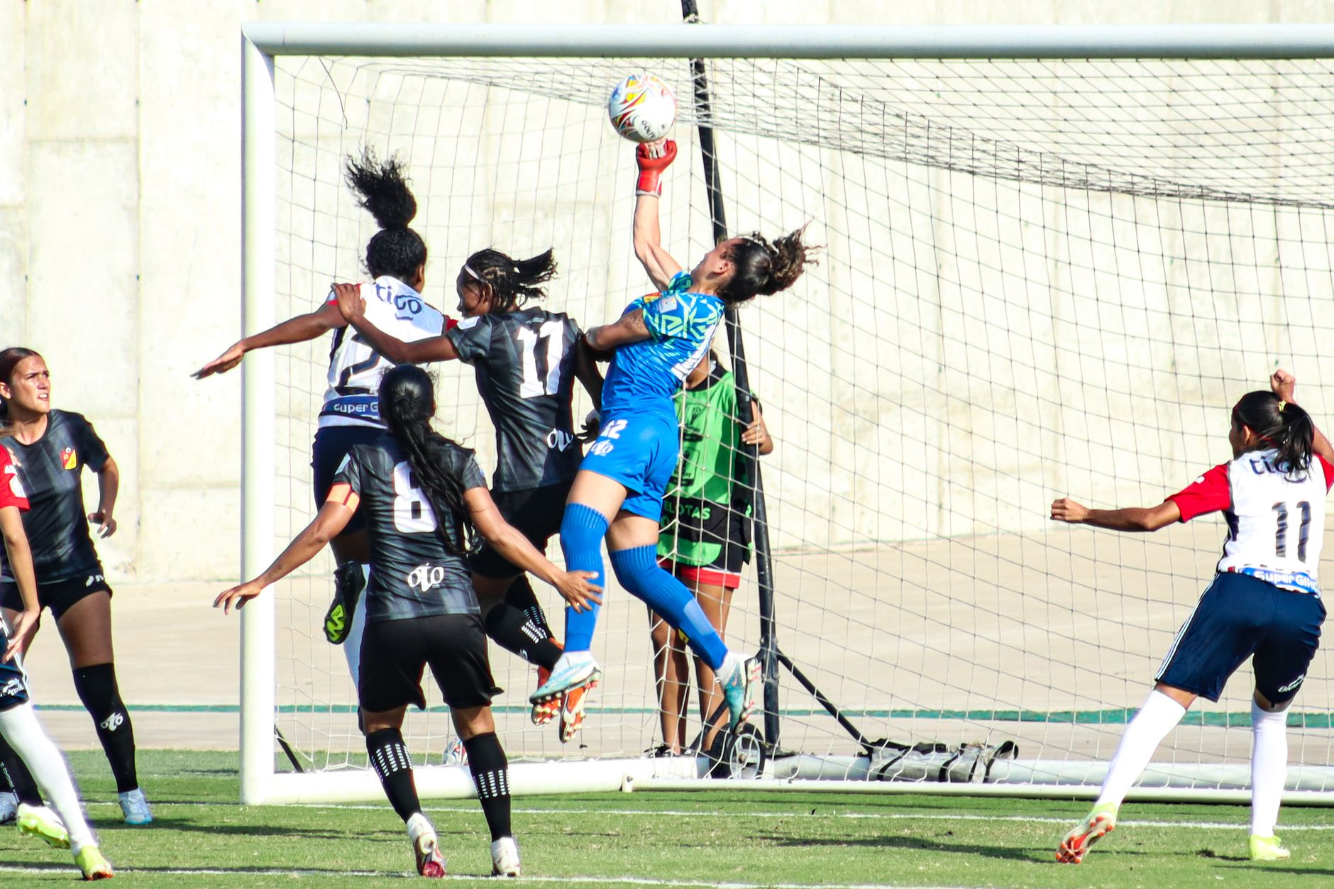 Goalkeeper leaps to make a save during an intense women's soccer match.
