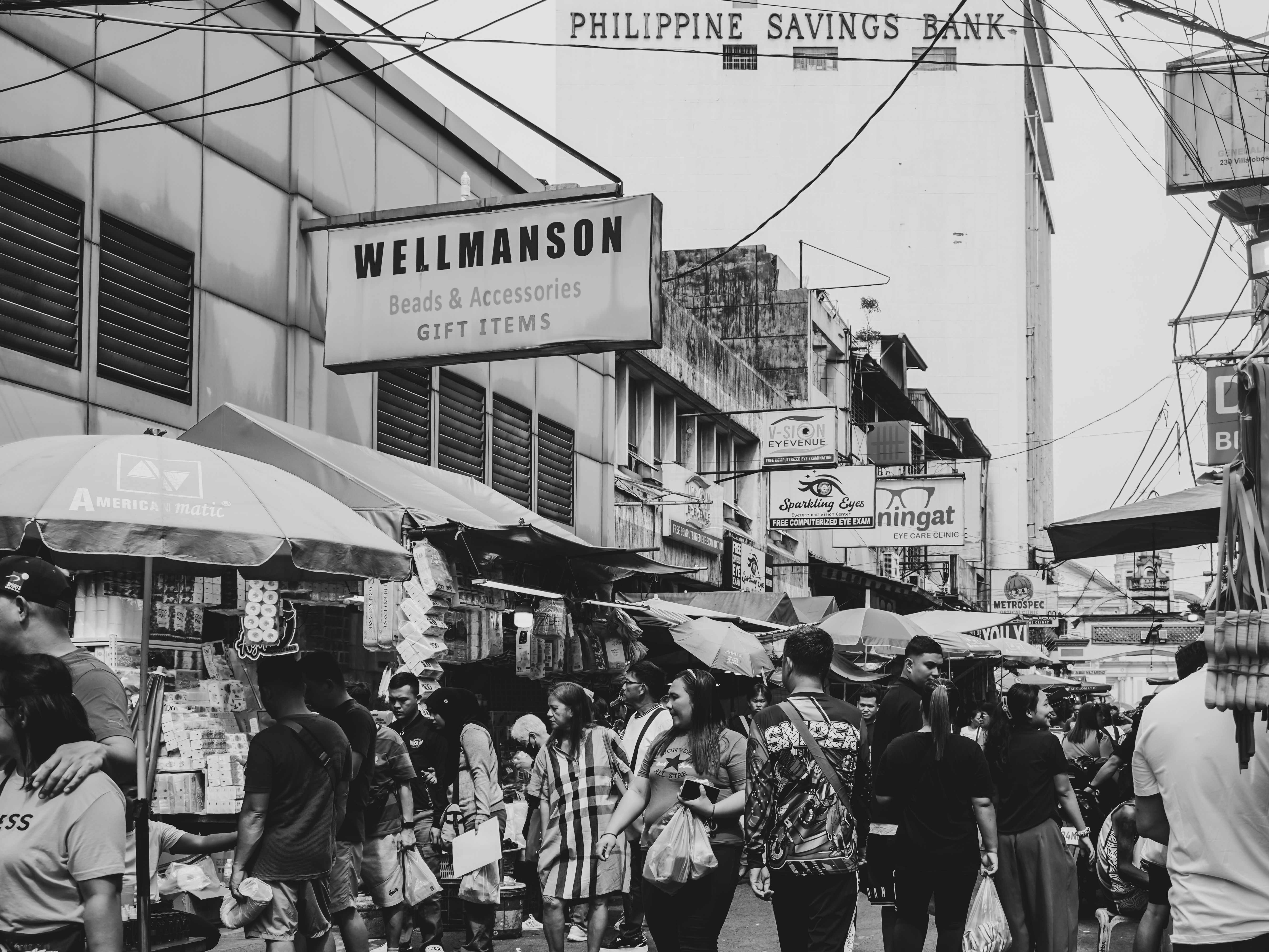 A lively street market in Manila, Philippines, bustling with people and vibrant activity captured in black and white.
