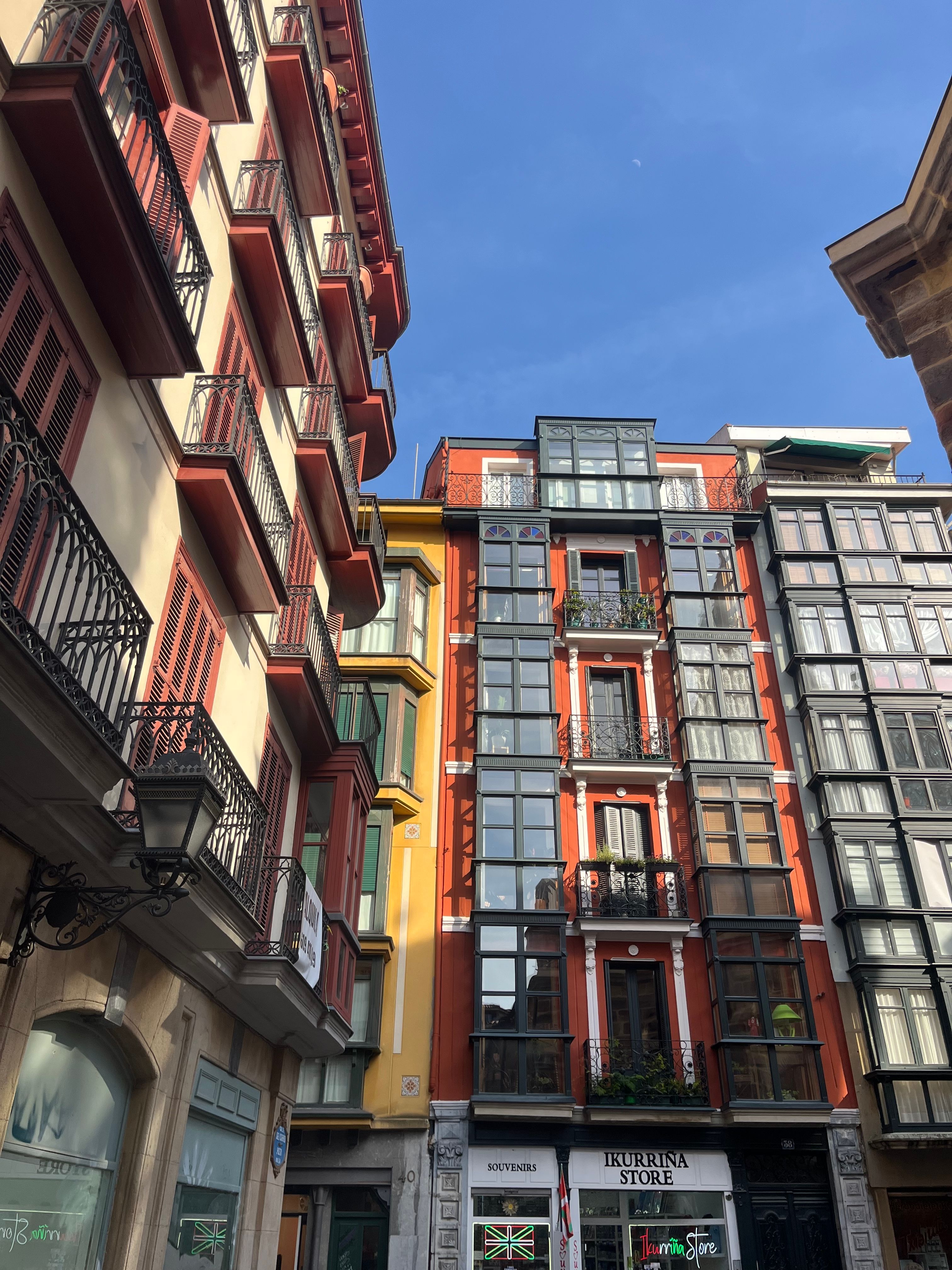 Vibrant facade of buildings in the historic streets of Bilbao under a clear blue sky.