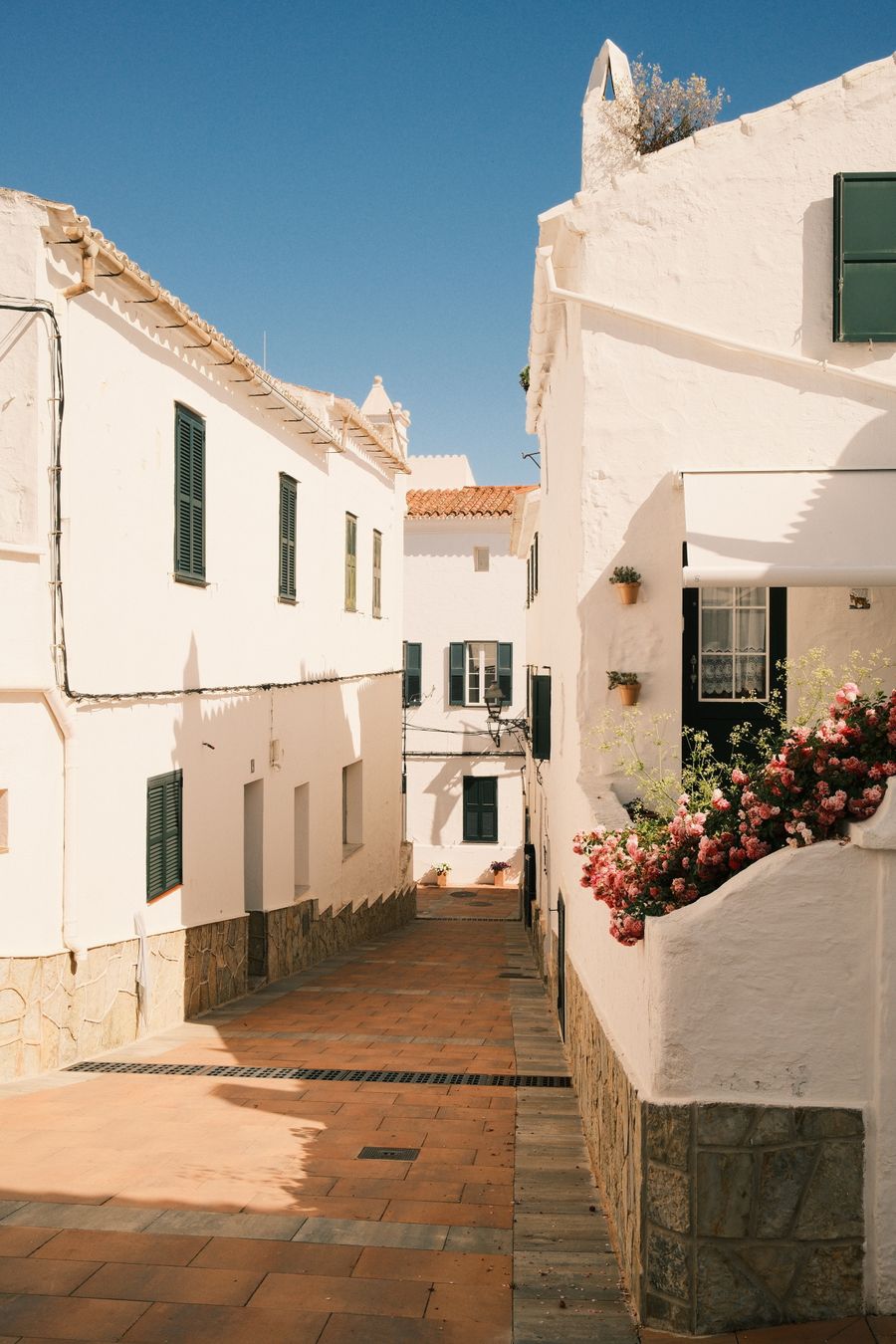 Calle mediterránea soleada con fachadas blancas